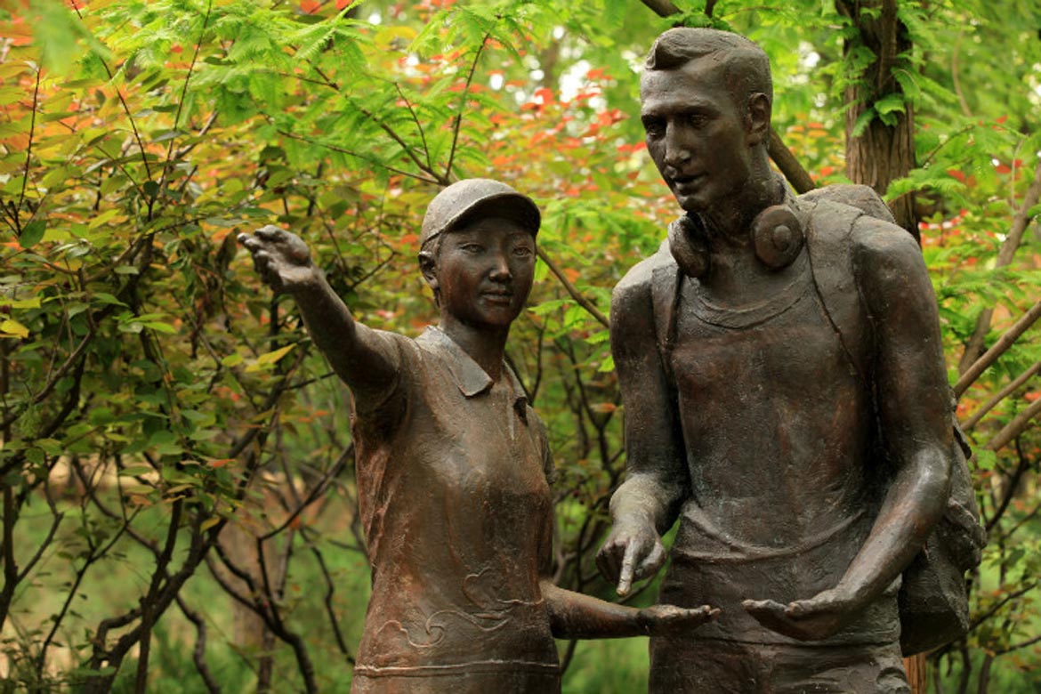 红领巾为外国友人指路的园林景观铸铜雕塑人物正面特写