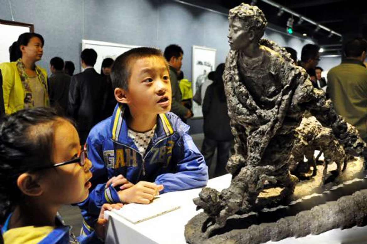 小孩在参观胡学富雕塑个人展览当中的放羊的少年雕塑作品