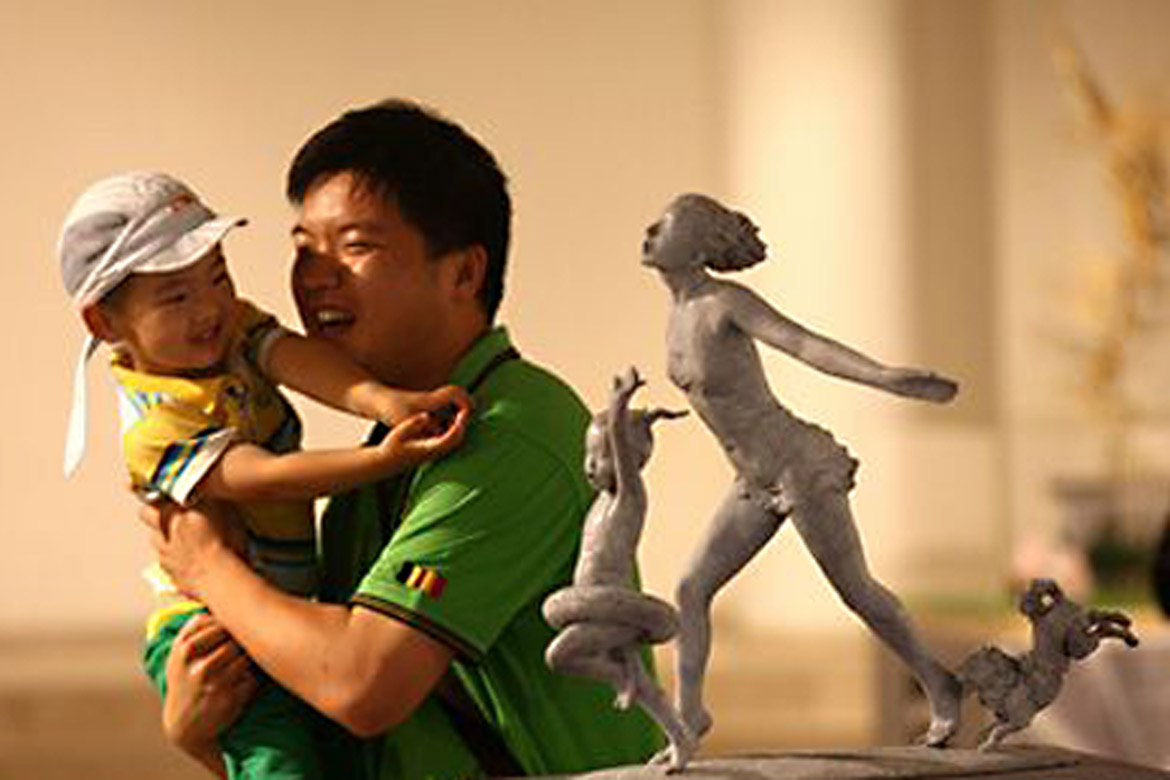 大人抱着小孩欣赏胡学富的雕塑个人展览人体雕塑作品